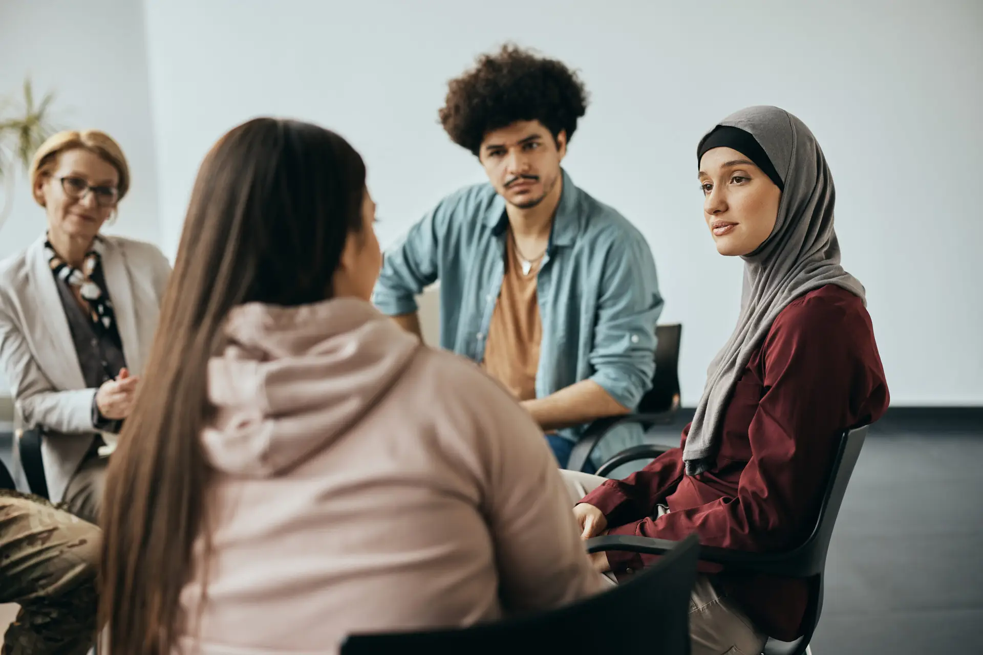multi ethnic people having counseling during group therapy meeting at community center.